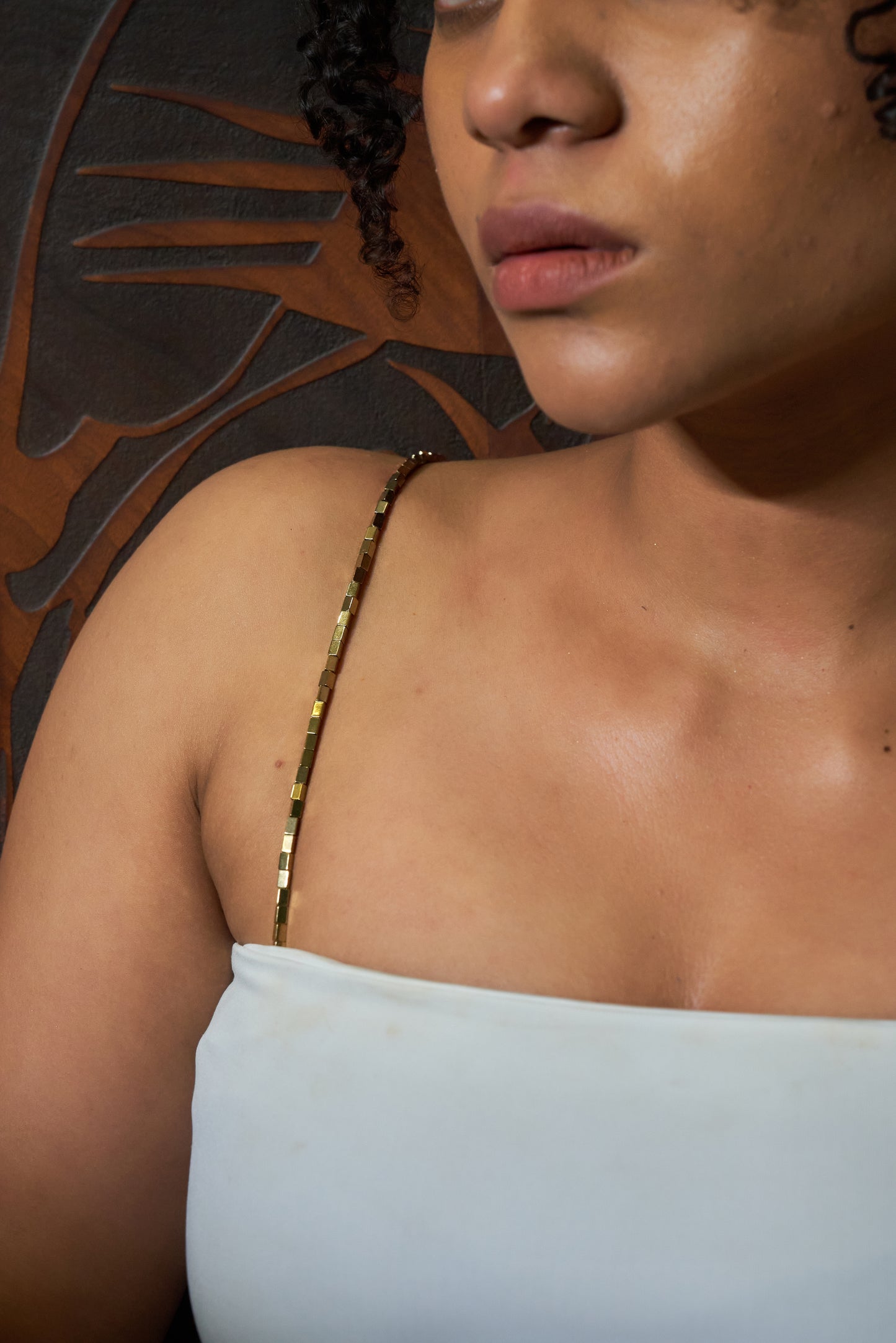 Model wearing a sleek, shimmery gold chain shoulder accessory styled as a bra strap replacement, designed to elevate sleeveless outfits.