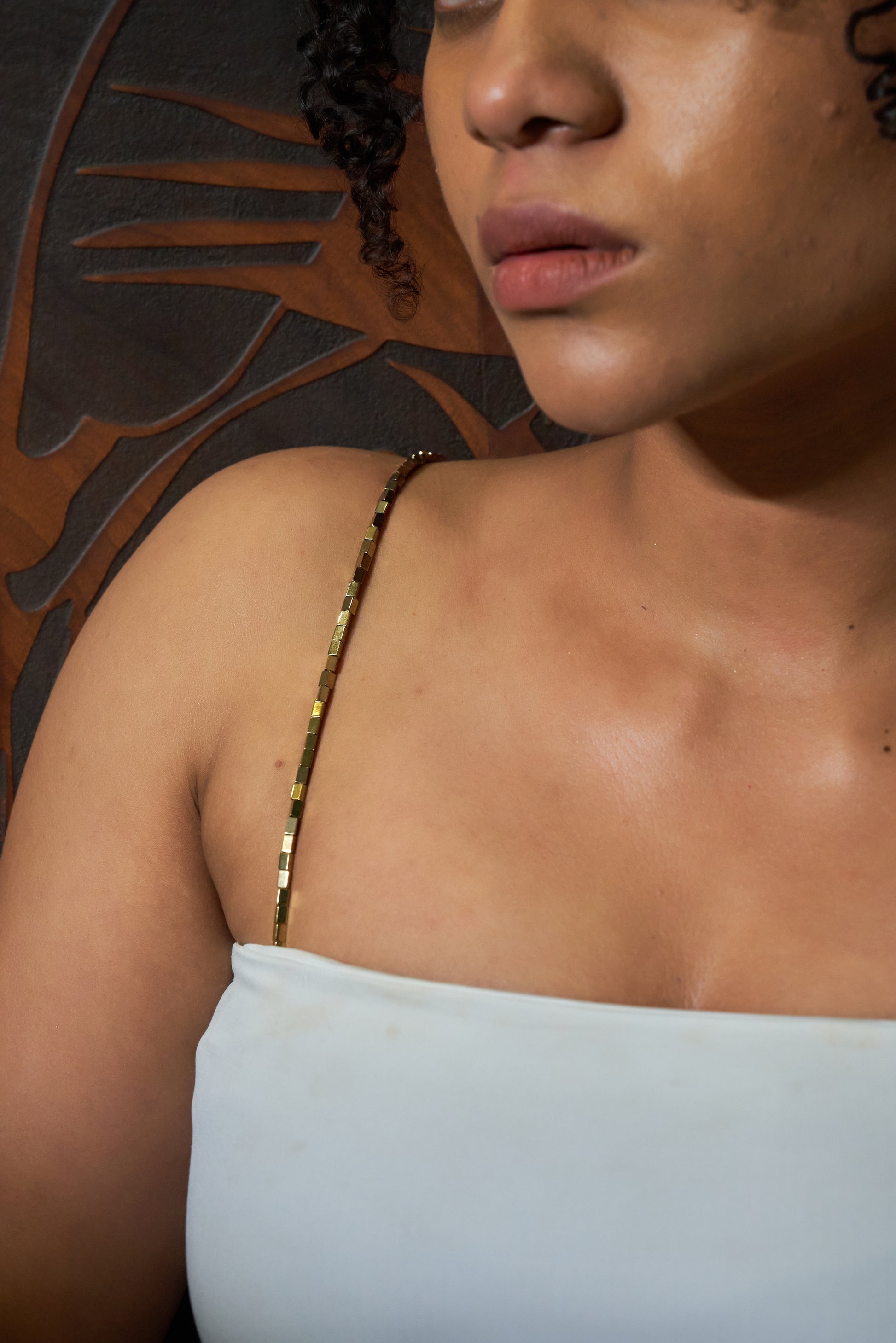Model wearing a sleek, shimmery gold chain shoulder accessory styled as a bra strap replacement, designed to elevate sleeveless outfits.