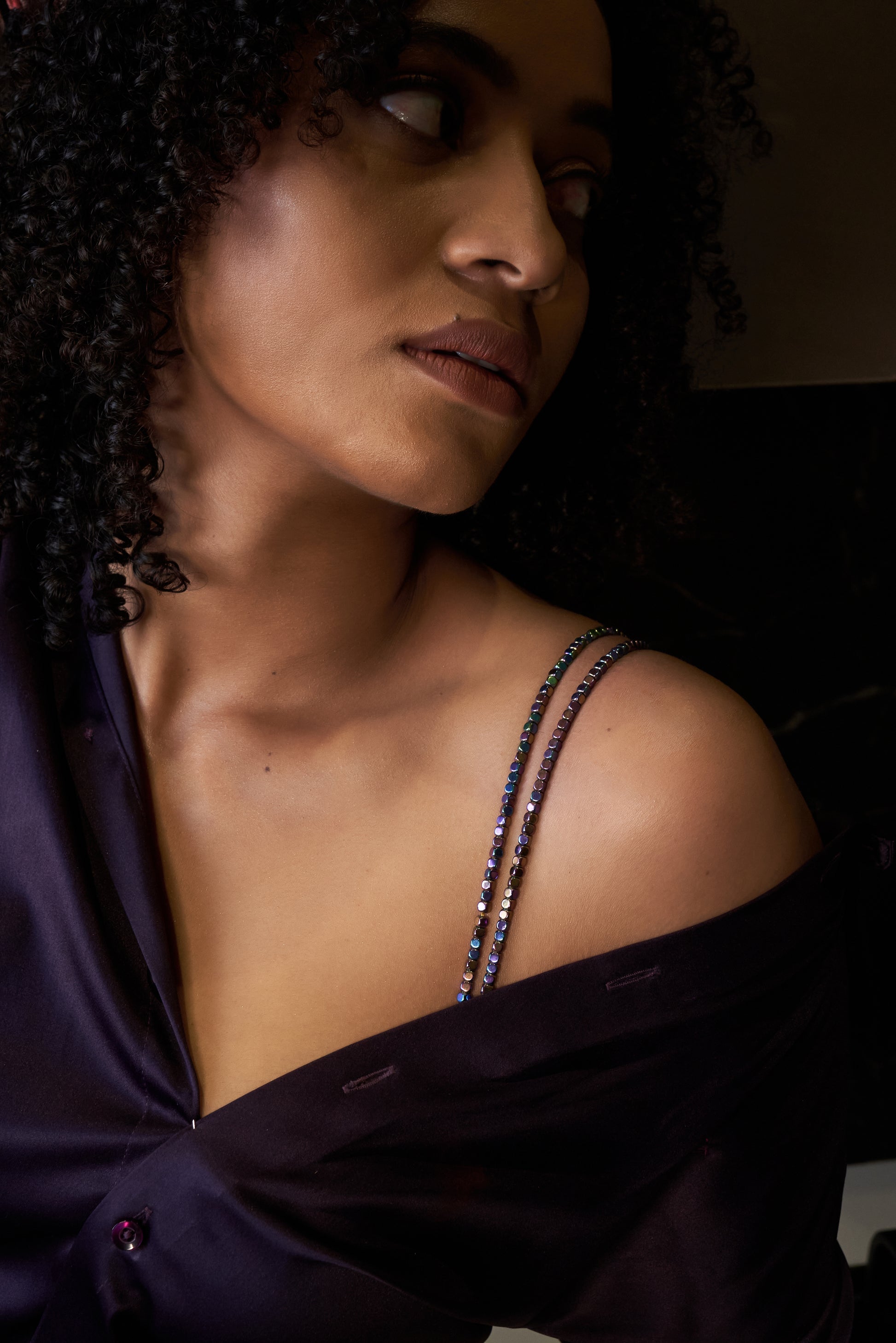 Woman wearing a dark purple off-shoulder top with thin straps.